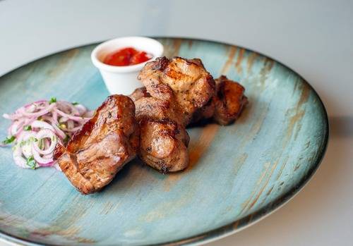 home bbq grills gilled meat with some red onions and a red salsa served on a blue plate